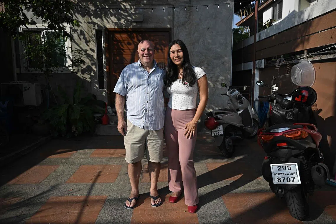 This photo taken on January 9, 2025 shows Ariya "Jin" Milintanapa (R) and Lee Ronald Battiata posing outside their family home in Bangkok. Hundreds of LGBTQ+ couples are set to marry in Thailand on January 23, as the country makes history by becoming the first country in Southeast Asia to legalise same sex marriage. (Photo by Lillian SUWANRUMPHA / AFP) / TO GO WITH Thailand-law-gender-marriage, FOCUS by Montira RUNGJIRAJITTRANON and Watsamon TRI-YASAKDA