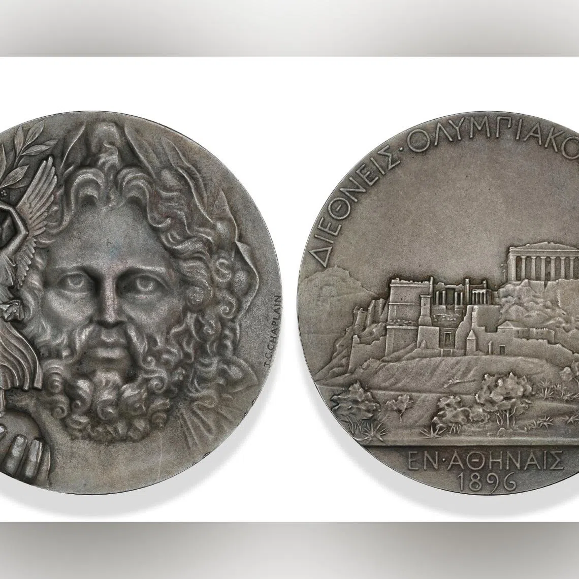 Engraved by French artist Jules-Clement Chaplain, the medal features Zeus holding a globe topped by Nike, the Goddess of Victory, brandishing an olive branch.
