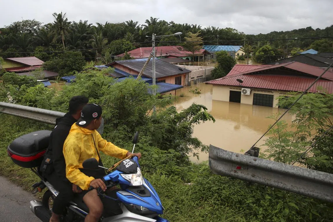 epa10501879 People look at a flooded residential area in Yong Peng, Johor, Malaysia, 04 March 2023. According to state media, more than 33,000 people were evacuated in four states affected by the floods. EPA-EFE/FAZRY ISMAIL
