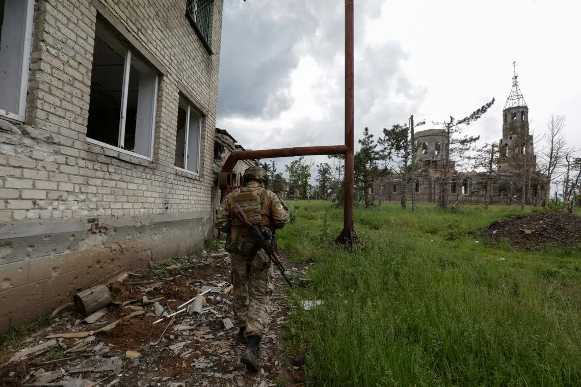A Ukrainian serviceman walks along a damaged building in a village in Donetsk, Ukraine, on June 1.
