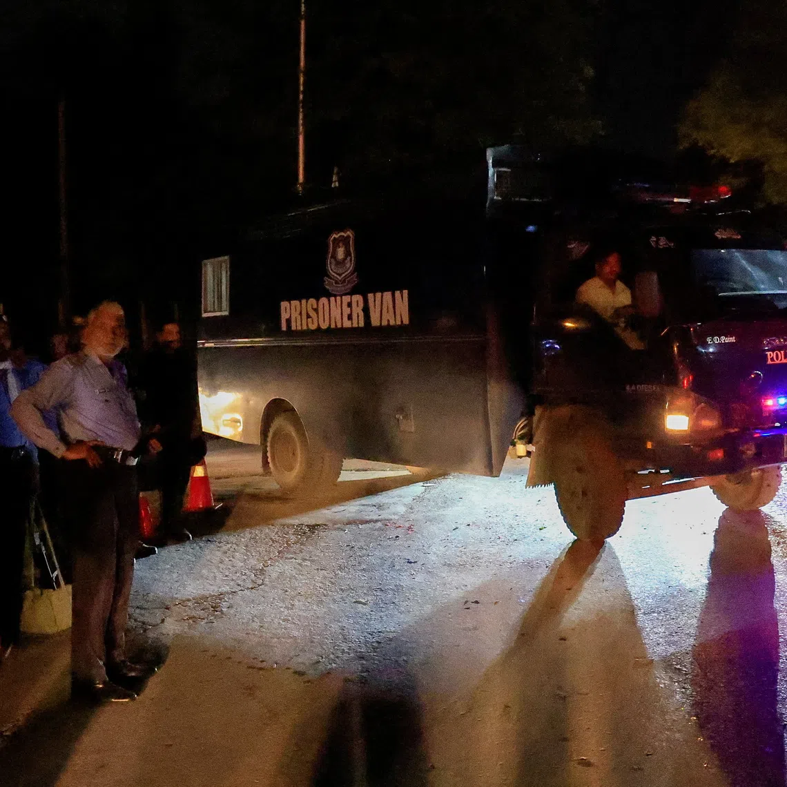 A prison van moves past police officers guarding the road leading to Shifa International Hospital on Aug 20.