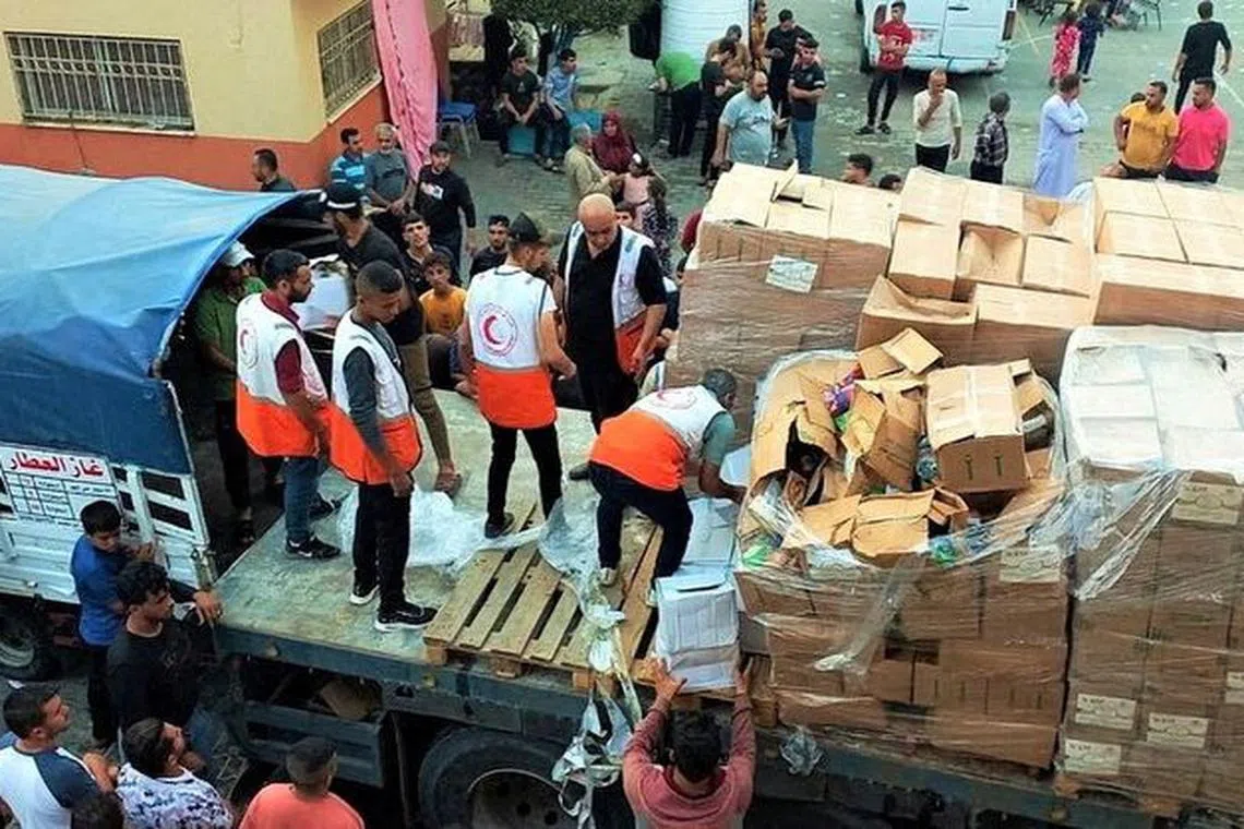 FILE PHOTO: Members of the Palestine Red Crescent Society distribute aid to people in Deir al-Balah, in the central Gaza Strip, in this handout picture released on October 25, 2023.  Palestine Red Crescent Society/Handout via REUTERS/File photo