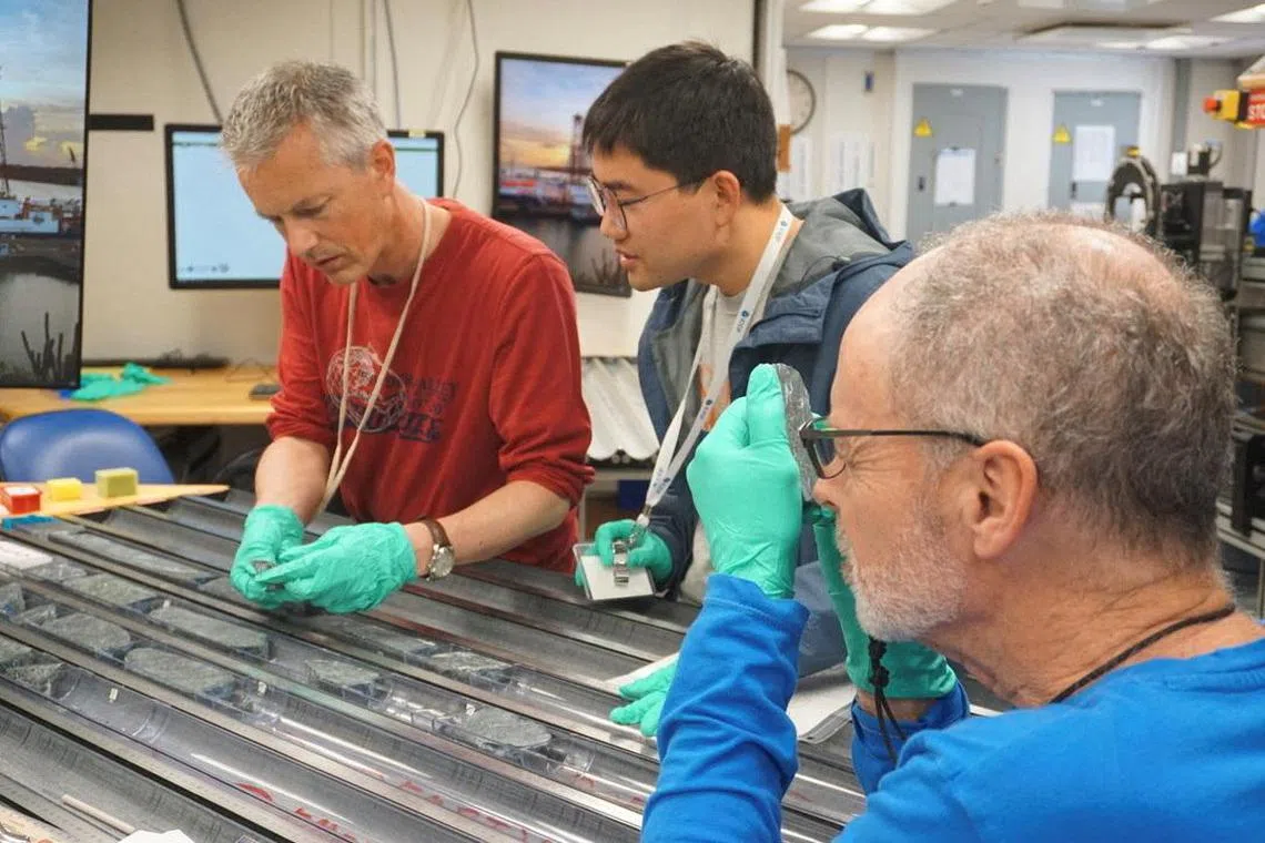 Geologist Johan Lissenberg from Cardiff University and two colleagues analyze rock from Earth’s mantle drilled from the Atlantic seabed aboard the ocean drilling vessel Joides Resolution above Atlantis Massif in the Atlantic Ocean in this handout photograph taken on May 4, 2023, and released on August 8, 2024. Scientists are analyzing the mantle rocks to establish their mineralogy and chemical makeup. Lesley Anderson/Handout via REUTERS    THIS IMAGE HAS BEEN SUPPLIED BY A THIRD PARTY. NO RESALES. NO ARCHIVES