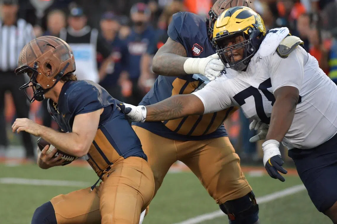 FILE PHOTO: Oct 19, 2024; Champaign, Illinois, USA;  Michigan Wolverines defensive lineman Kenneth Grant (78) reaches for Illinois Fighting Illini quarterback Luke Altmyer (9) during the second half at Memorial Stadium. Mandatory Credit: Ron Johnson-Imagn Images/File photo