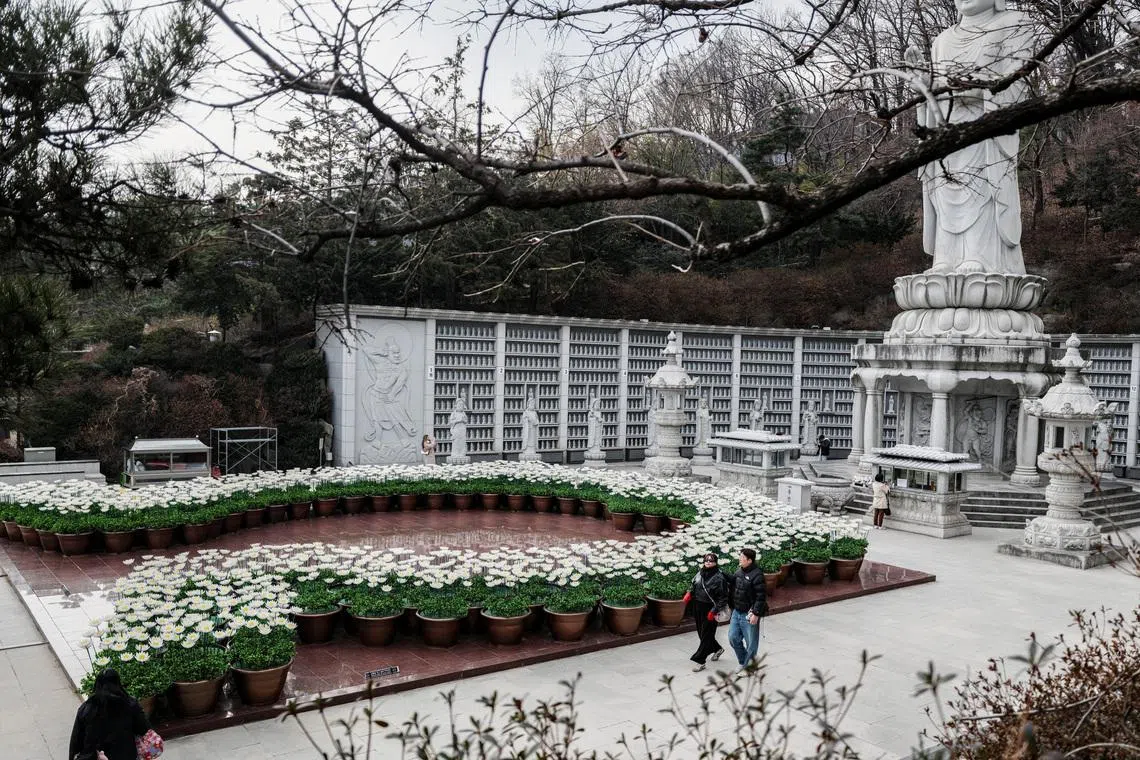 People walk past Buddhist statue of Bongeunsa Temple in Seoul, South Korea, March 9.