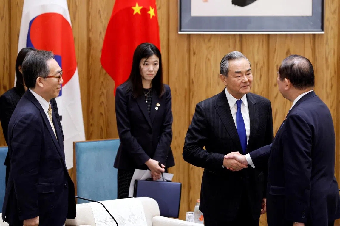 Japanese PM Shigeru Ishiba shakes hands with Chinese Foreign Minister Wang Yi in Tokyo, on March 21.