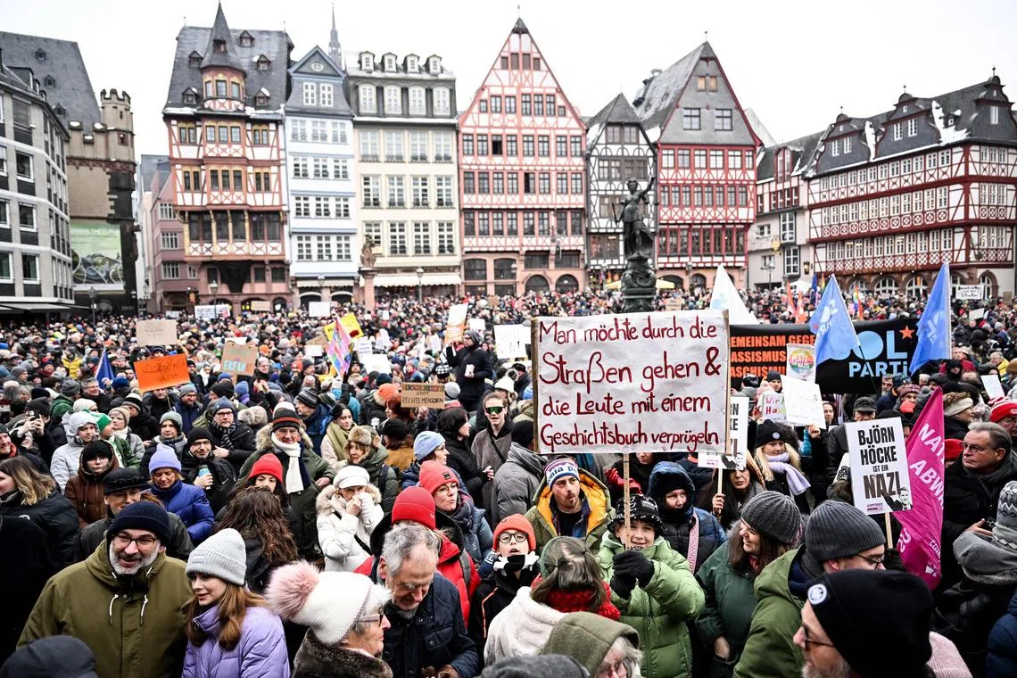 Participants hold up a placard reading, "One would like to go through the street and hit people with a history book", as they protest against racism and far-right politics in Frankfurt, Germany.