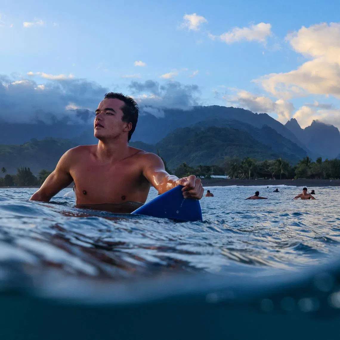 Manakei waits for a wave as he surfs at a local beach in Papara, Tahiti, July 24, 2024. The Polynesian Triangle encompasses some 10 million square miles of the Pacific Ocean, with its people, who trace their lineage back to a spiritual homeland, closely connected by language, culture and their intimate knowledge of the moana, the ocean. \"Only kings were able to surf here before,\" said local Tereva David, 35. \"For us, surfing is sacred, it's the culture - like dancing, like canoe paddling, like singing, like making food for everybody.\" REUTERS/Carlos Barria