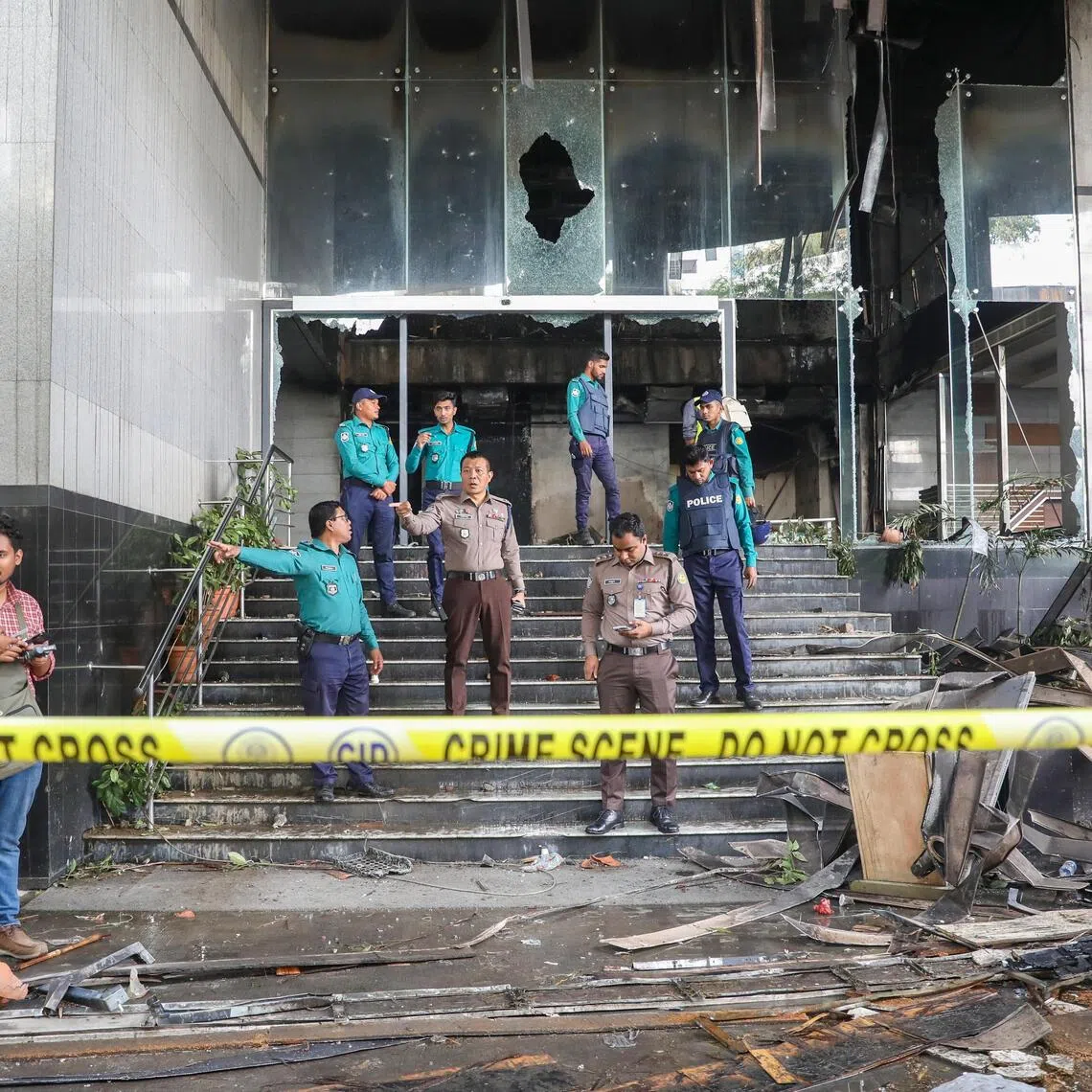 Bangladeshi police stand guard in front of the burnt office of the Daily Star newspaper.