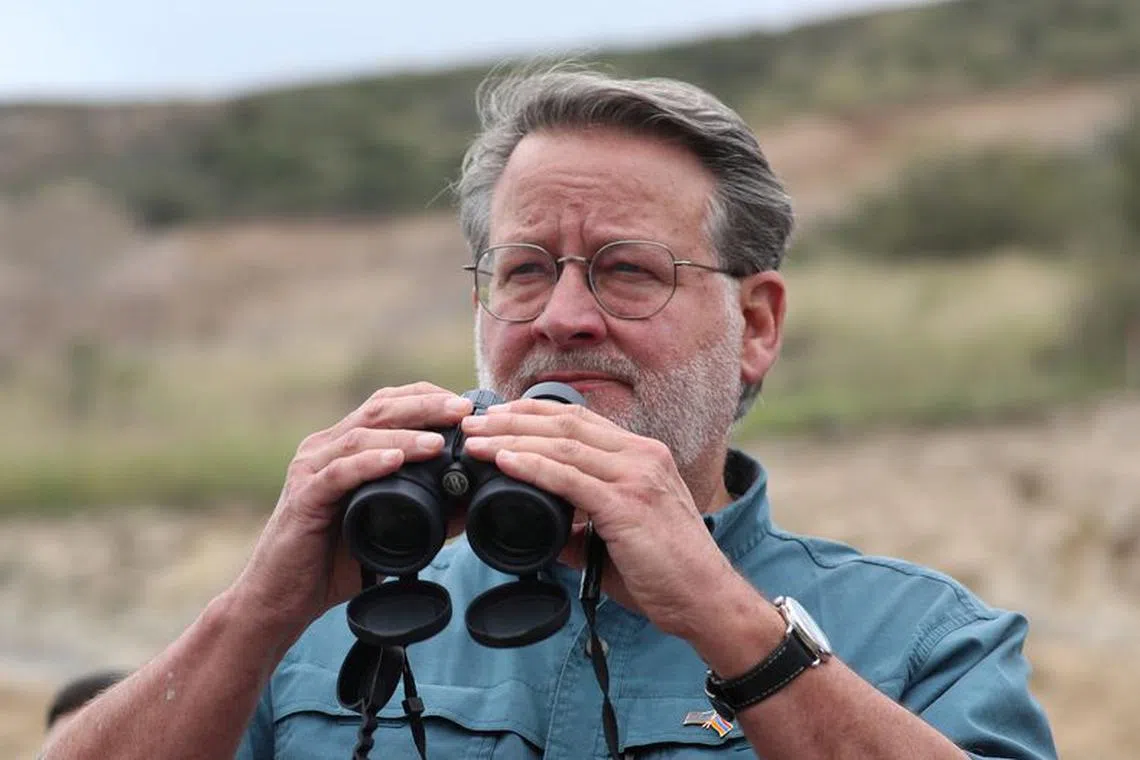 Gary Peters, a U.S. senator leading a congressional delegation to the Armenia-Azerbaijan frontier to monitor the situation in Nagorno-Karabakh, uses binoculars to look at a border-crossing point on a road near the village of Kornidzor, Armenia, September 23, 2023. REUTERS/Irakli Gedenidze