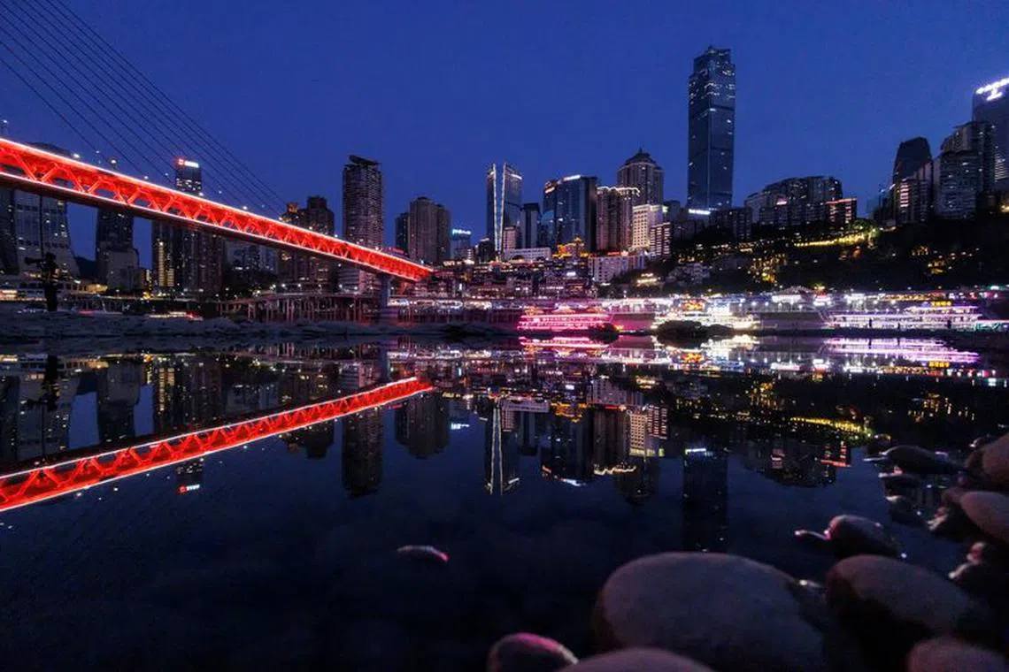 The city skyline is reflected in a pool left on the dry riverbed of the receding Jialing river in Chongqing, China, August 20, 2022. REUTERS/Thomas Peter/File Photo