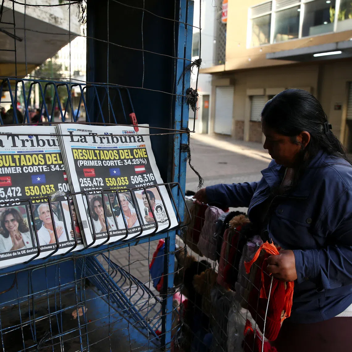 A woman sets up a newspaper stand that displays cover stories on the preliminary results of the general election in Tegucigalpa, Honduras, December 1, 2025. REUTERS/Jose Cabezas