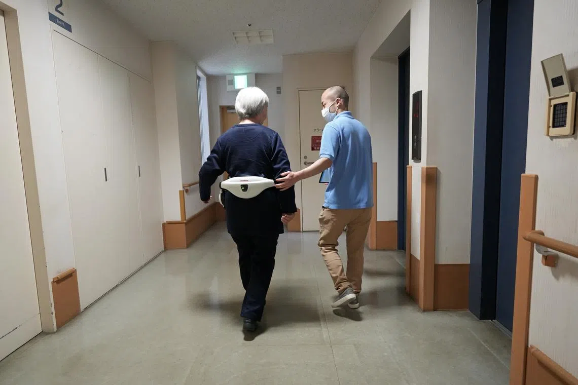 A resident walking with the support of a Honda walking support device at the Shintomi nursing home in Tokyo, Japan, April 7, 2023.