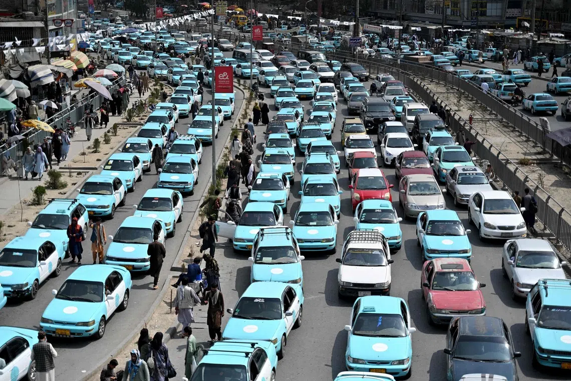 TOPSHOT - Commuters riding blue taxis wait in a traffic jam in Kabul on September 14, 2026. (Photo by Wakil KOHSAR / AFP)