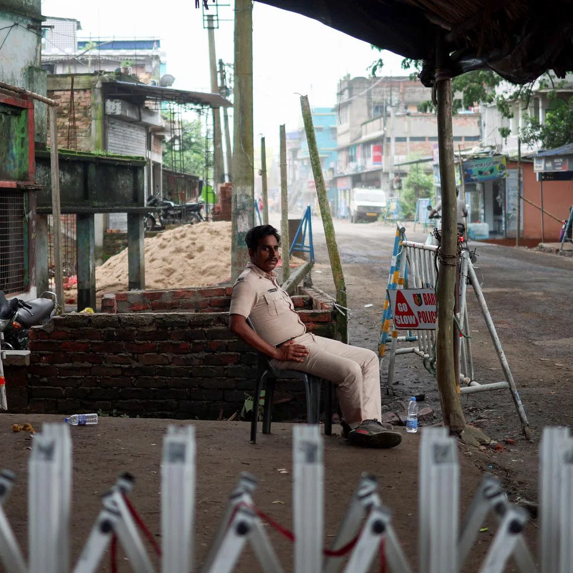 A police officer sits as he guards a street following the rape and murder of an 11-year-old girl in a town near Kolkata on July 11.