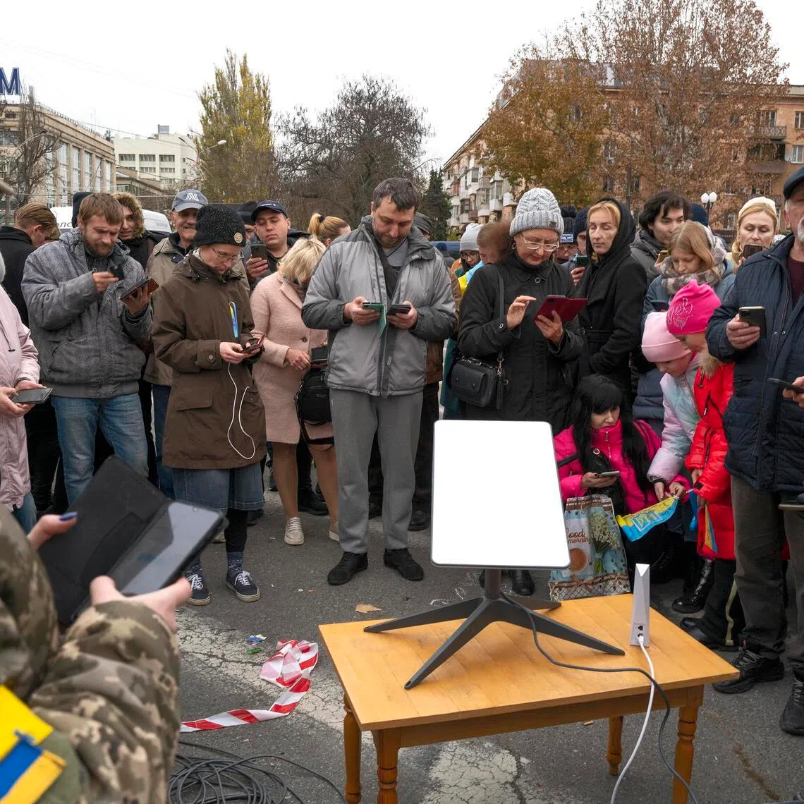 Ukrainians gather around a Starlink satellite antenna for internet connection in Kherson, Ukraine, on Nov 13, 2022. Moscow's  forces fighting in Ukraine are experiencing outages on the front, Russian military bloggers said, days after Elon Musk said his satellite service had cut them off. 