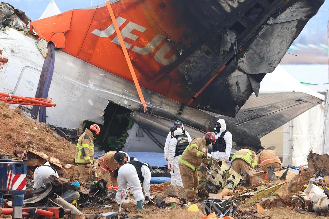 Forensic experts, police investigators and firefighters work at the site of the deadly plane crash at Muan International Airport.