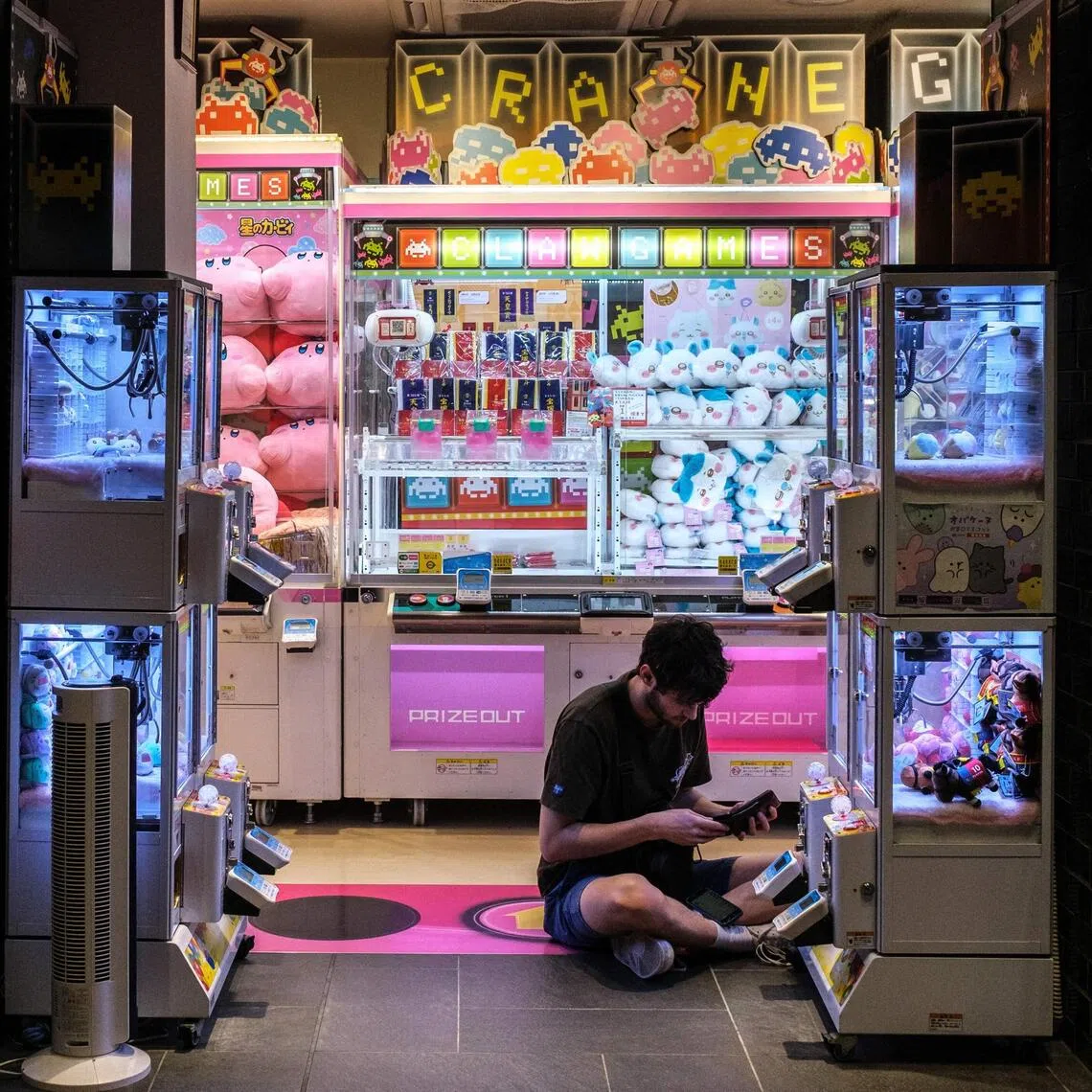 A man pays to play a claw crane game machine inside a shop at the Akihabara district of Tokyo.