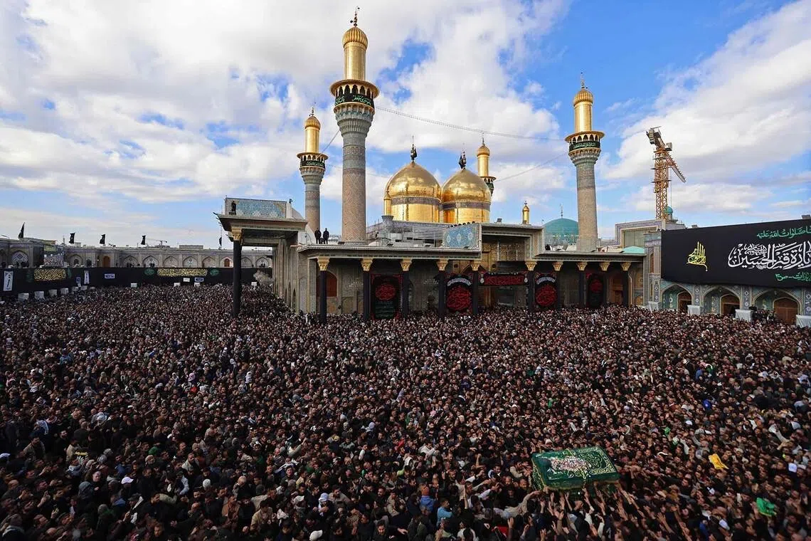 TOPSHOT - Shiite Muslim pilgrims march with a symbolic coffin in the shrine of the 8th-century Imam Musa al-Kadhim, during the annual commemoration of his death on 25 Rajab according to the Muslim Hijri calendar, in the Kadhimiya district of northern Baghdad on January 15, 2026. Pilgrims from various Iraqi provinces annually undertake a march on foot to reach the shrine to commemorate the death of Imam Kadhim, who is believed to have been poisoned by agents of the ruling Abbasid caliph Harun al-Rashid. (Photo by AHMAD AL-RUBAYE / AFP)