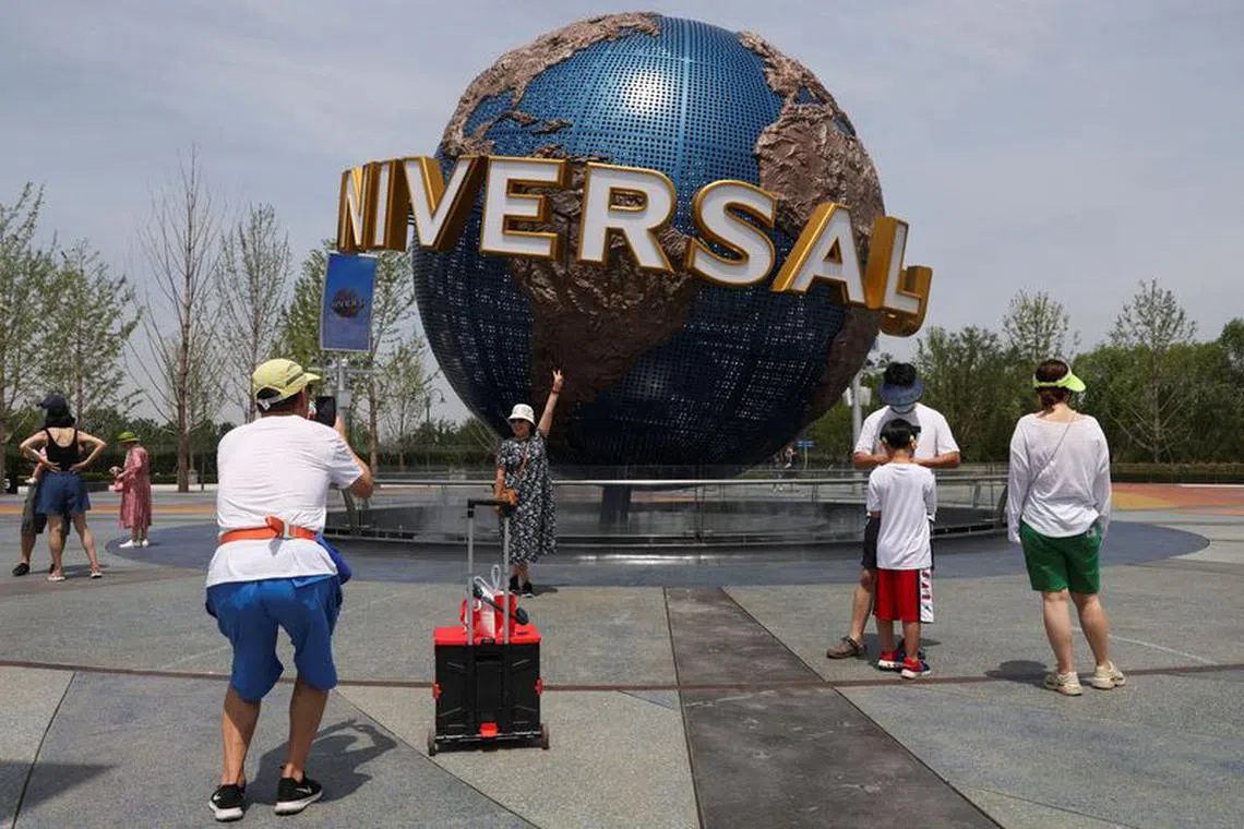 FILE PHOTO: A tourist poses in front of a sign of the Universal Resort, as the Universal Studios theme park reopens to the general public, following the coronavirus disease (COVID-19) outbreak in Beijing, China June 25, 2022. REUTERS/Tingshu Wang/file photo