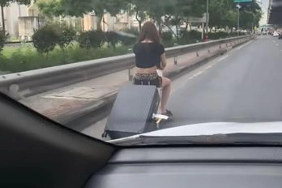 A woman was filmed riding on a suitcase on Bangkok’s busy Vibhavadi Rangsit Road near Don Mueang International Airport.