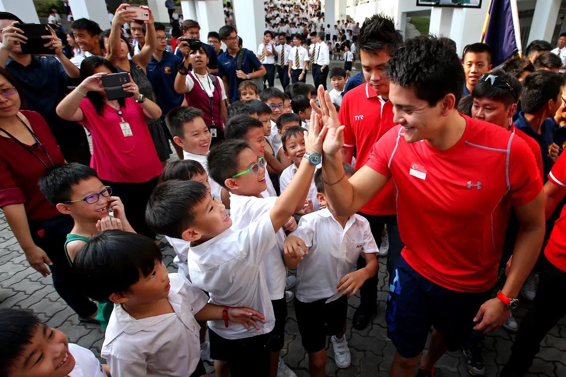 Singapore swimmer and Olympic gold-medalist Joseph Schooling giving a high-five to his young fans during a visit to his alma mater Anglo-Chinese School ( Junior) on Aug 16, 2016.