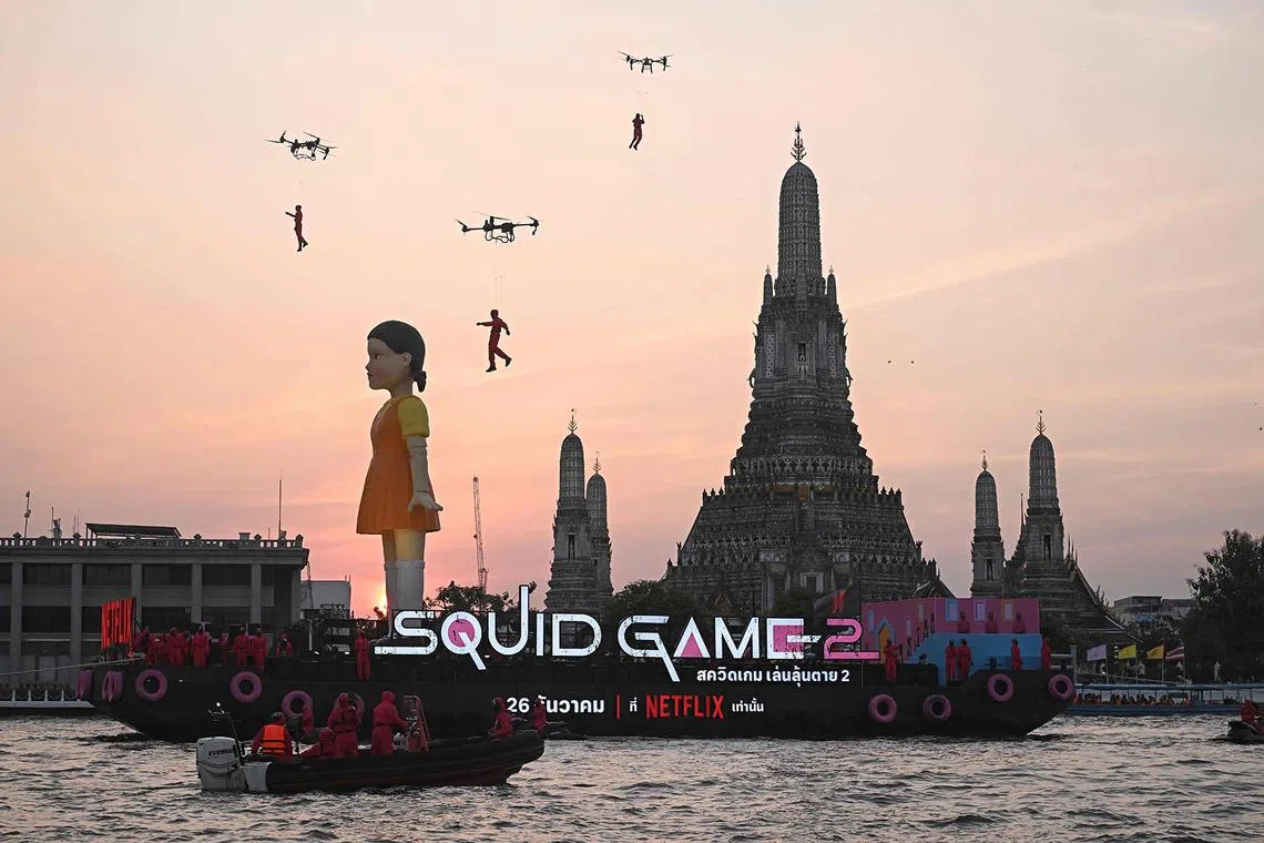 A 12 meter-tall statue of Young-hee, the iconic doll from Netflix’s South Korean TV series “Squid Game”, is seen on a barge in front of Wat Arun temple on the Chao Prayer River ahead of the launch of Season 2, in Bangkok on December 19, 2024. (Photo by Lillian SUWANRUMPHA / AFP)