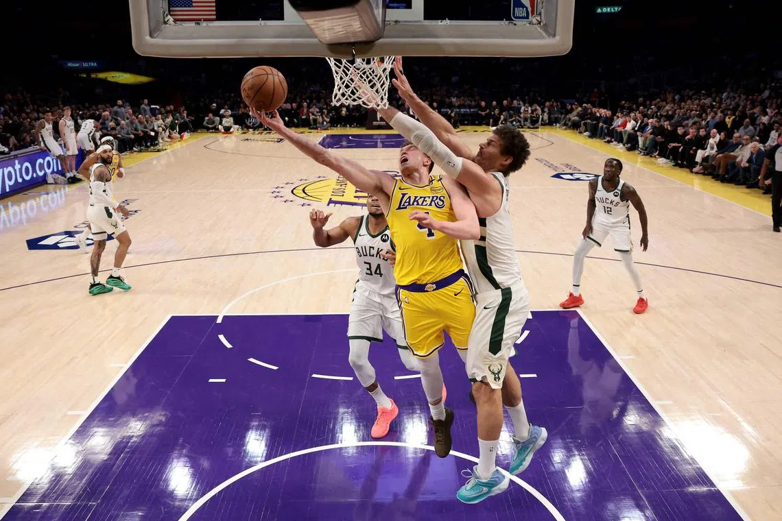 Dalton Knecht of the Los Angeles Lakers drives to the basket against Brook Lopez of the Milwaukee Bucks during the first quarter at Crypto.com Arena.