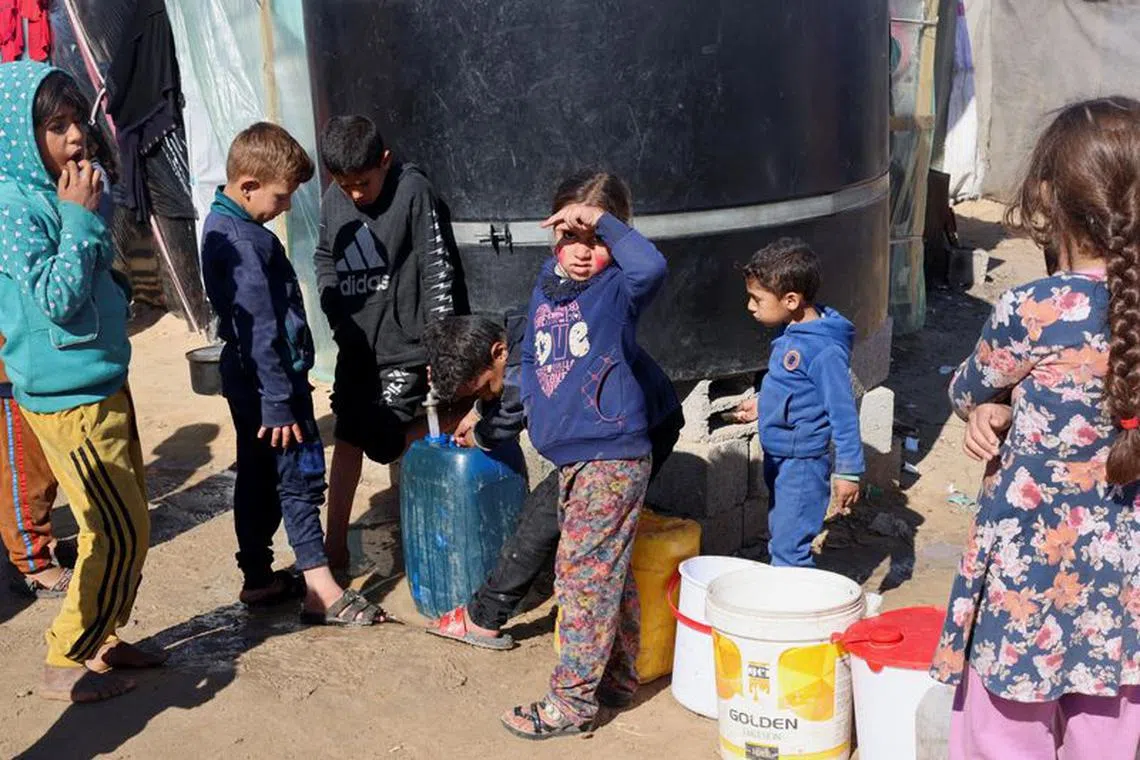 Displaced Palestinian children, who fled their houses due to Israeli strikes, wait to collect water amid shortages, at a tent camp in Rafah in the southern Gaza Strip February 1, 2024. REUTERS/Saleh Salem
