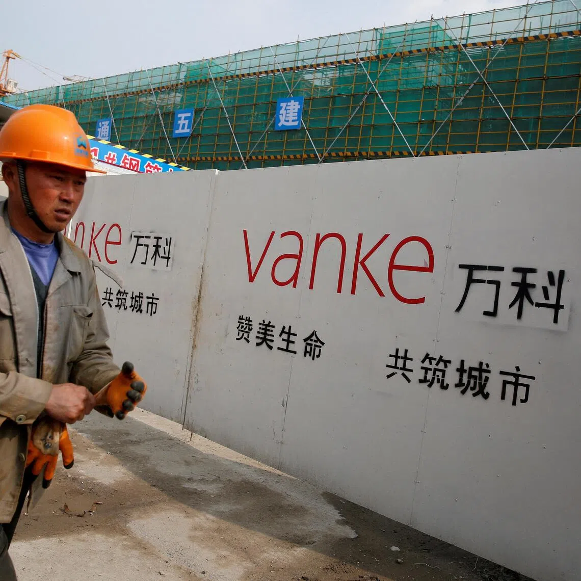 FILE PHOTO: A person walks past by a gate with a sign of Vanke at a construction site in Shanghai, China, March 21, 2017. Picture taken March 21, 2017. REUTERS/Aly Song/File Photo