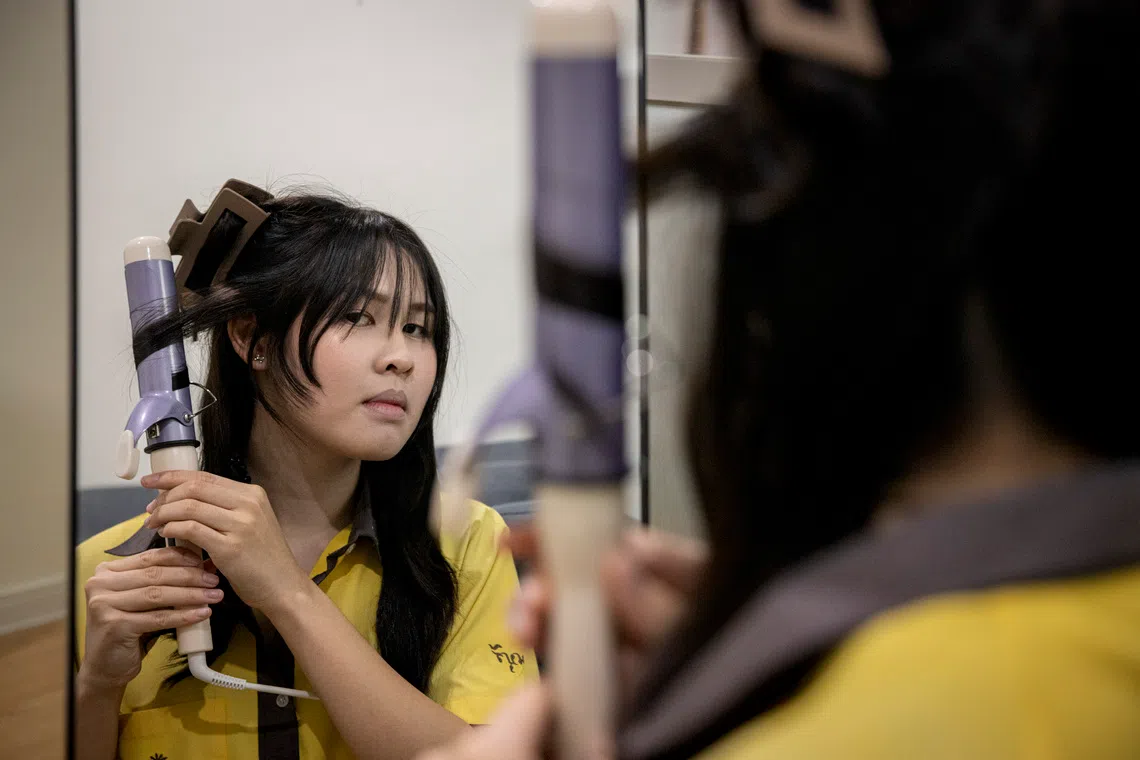 Phatit Kalaphakdee, who goes by Rin, styles her hair before school in Bangkok on July 7.