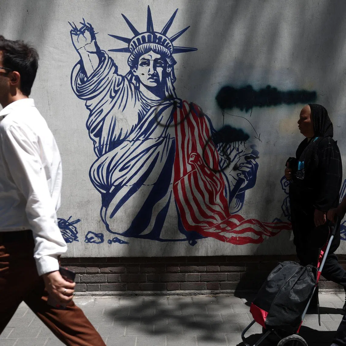 People walk past an anti-US mural on a street in Tehran on June 1.