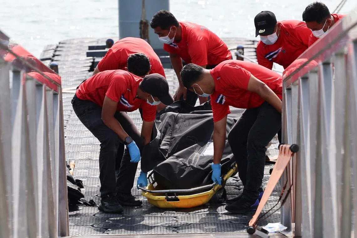 Rescuers carry the body of a Rohingya refugee who died after a boat he was on sank in waters near the Thai–Malaysian border.
