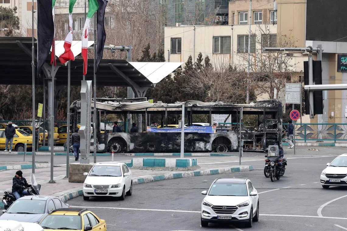 Traffic driving past the wreckage of a burnt-out bus in Tehran's Sadeghieh Square on Jan 15.