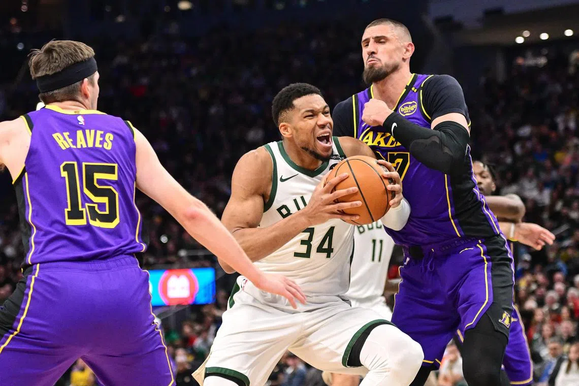 Milwaukee Bucks forward Giannis Antetokounmpo (No. 34) drives to the basket between Los Angeles Lakers guard Austin Reaves (No. 15) and centre Alex Len.