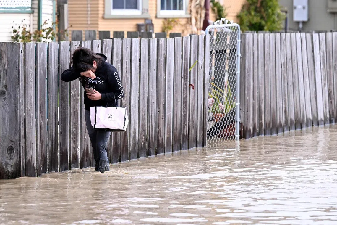 Naomi Rodriguez treads through flood waters to reach her home in the Pajaro area of Watsonville, California, on March 11, 2023. 