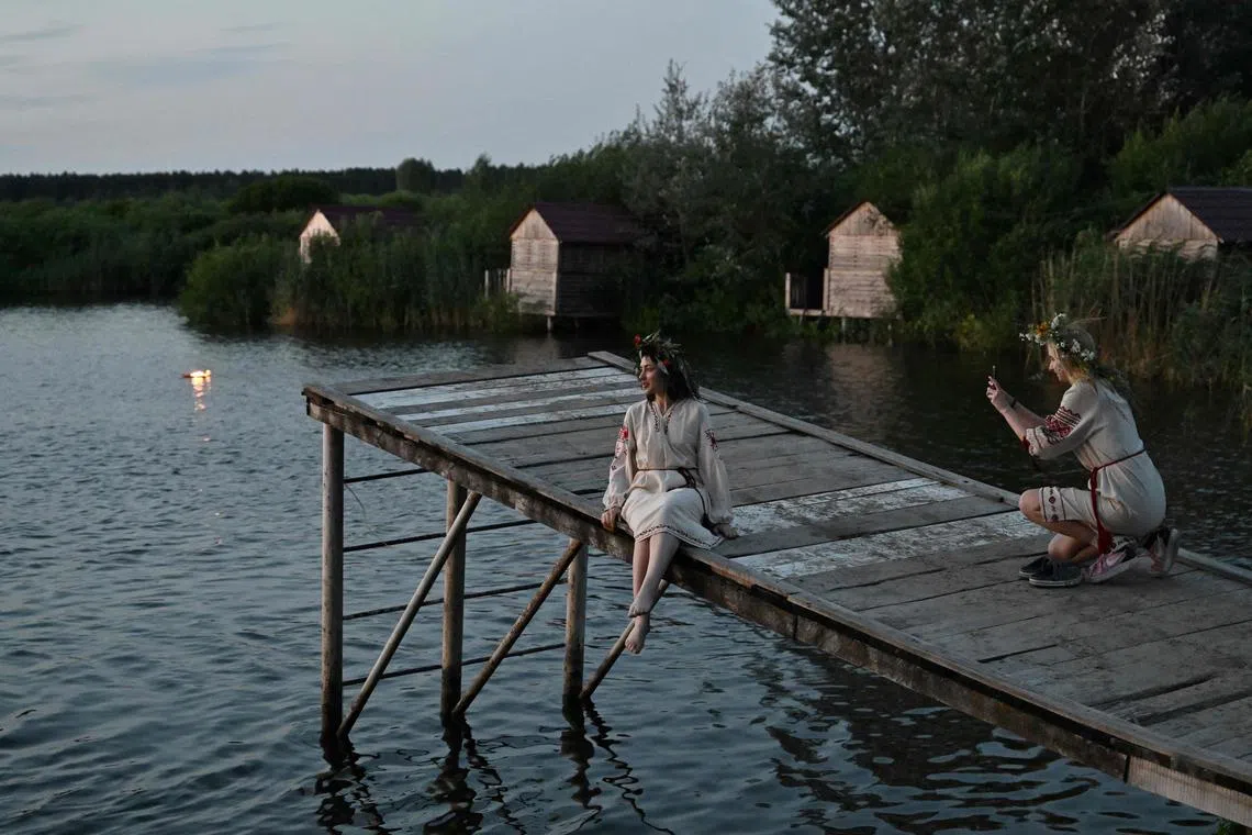 Women wearing traditional Ukrainian clothes attend Kupala night celebrations after volunteering to clear debris from destroyed buildings, near Yagidne, Chernihiv region on July 8, 2023, amid the Russian invasion of Ukraine. 