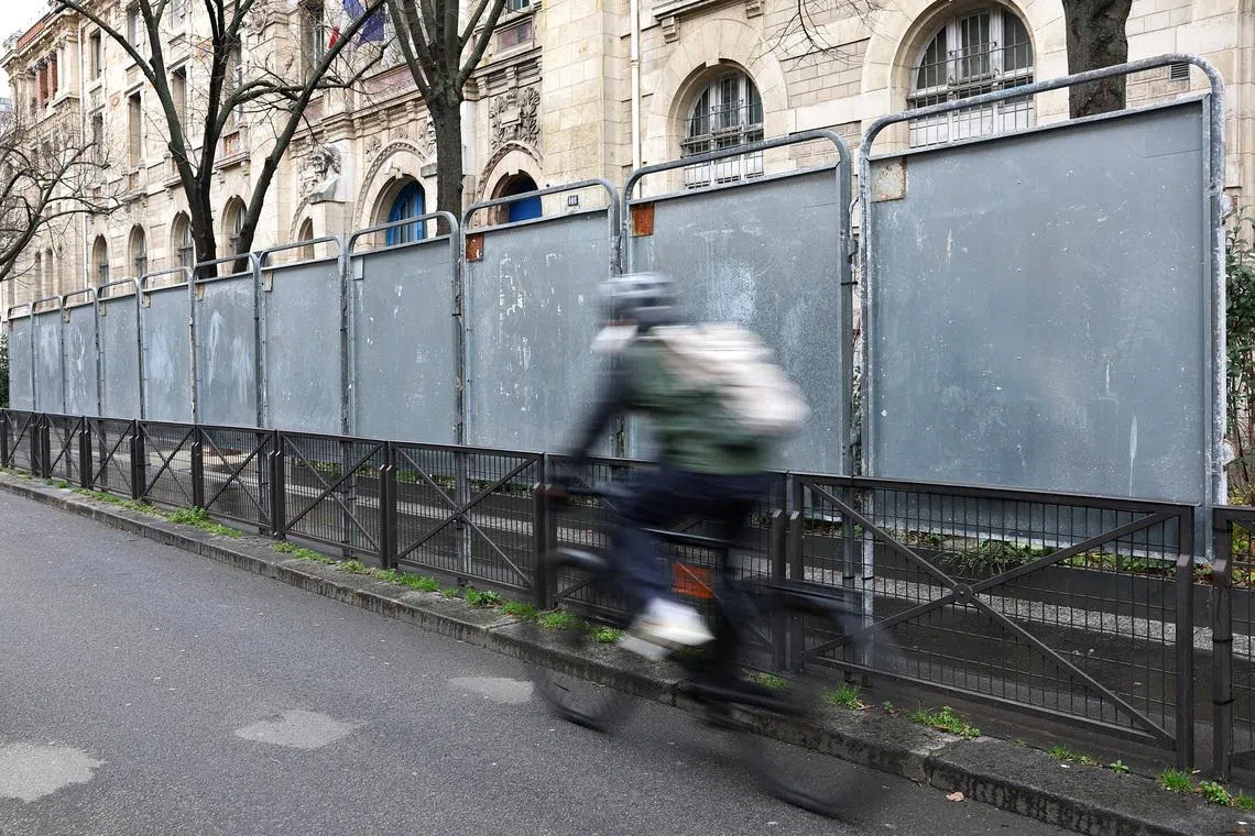 FILE PHOTO: A man rides his bicycle past newly installed electoral campaign panel boards ahead of the upcoming mayoral elections in Paris, France, February 24, 2026. REUTERS/Abdul Saboor/File Photo