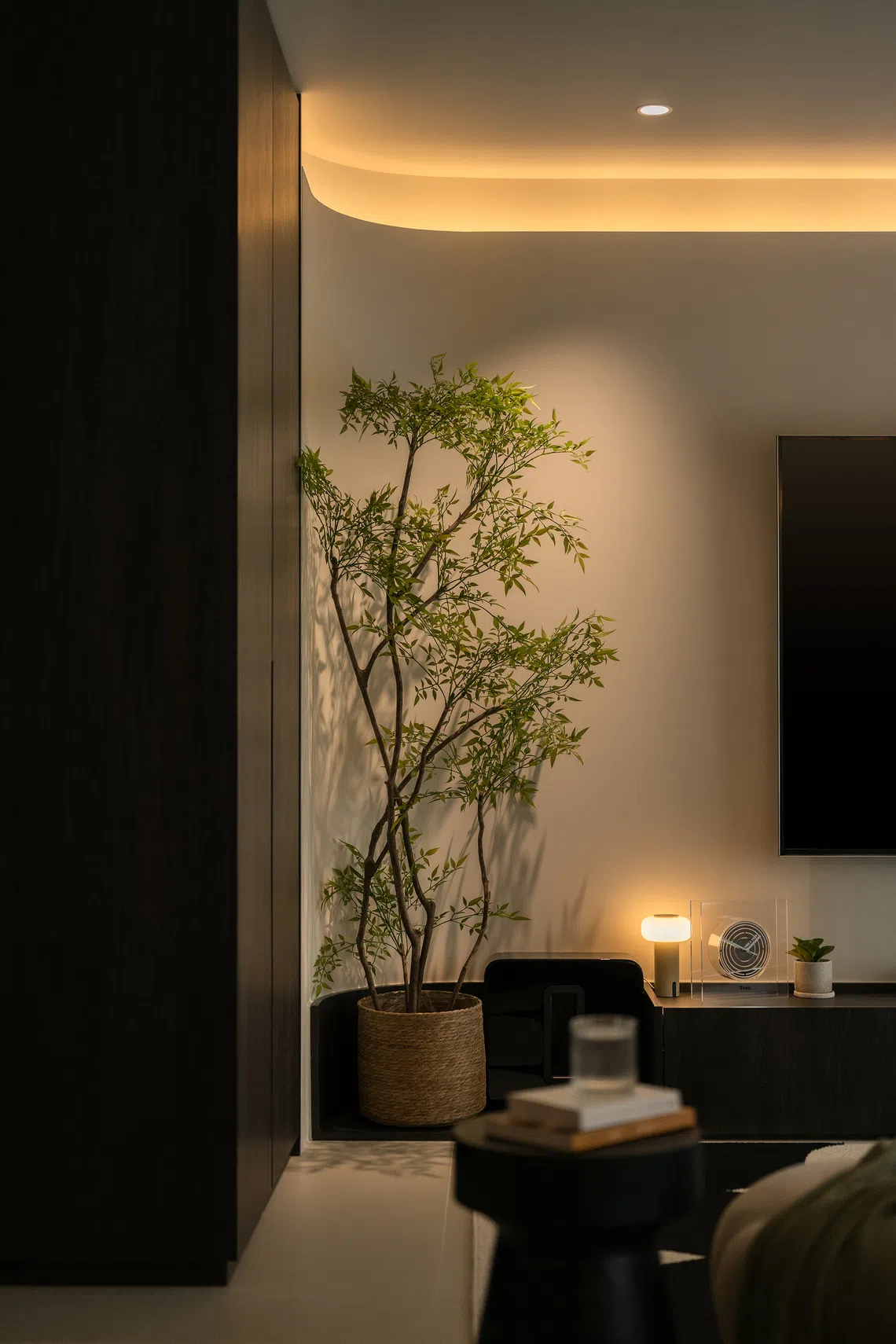 A curved corner at the TV feature wall introduces softness, highlighted by warm cove lighting.