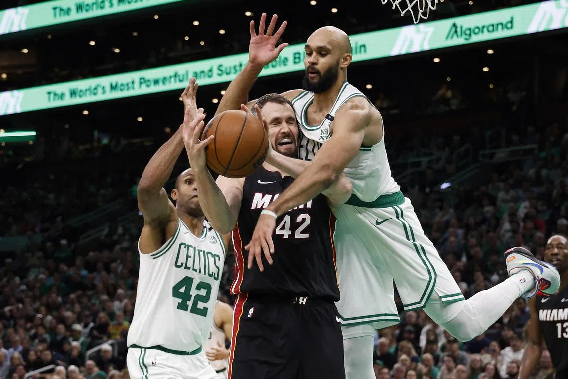 Boston Celtics guard Derrick White jumping in to try to knock the ball away from Miami Heat forward Kevin Love  during their NBA clash at TD Garden on Friday.