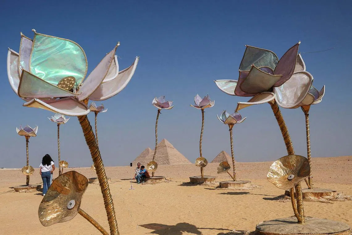 People visit an art installation by visual artist Shila Shivo titled "Pulse and Blood" during the fourth edition of "Forever is Now", an international art exhibition provided by Art D'Egypte that reimagines Egypt's ancient civilization through contemporary art in Giza Pyramids, on the outskirts of Cairo, Egypt, November 4, 2024. REUTERS/Amr Abdallah Dalsh TPX IMAGES OF THE DAY