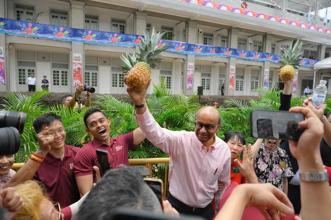 Tharman Shanmugaratnam holding up a pineapple, his presidential symbol, in front of his supporters.