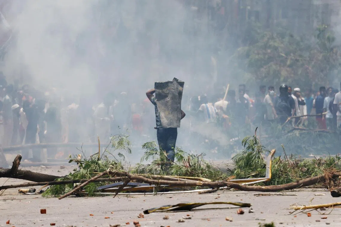 A protester covers himself with a metal sheet as violence erupts across Bangladesh over a civil service quota system.