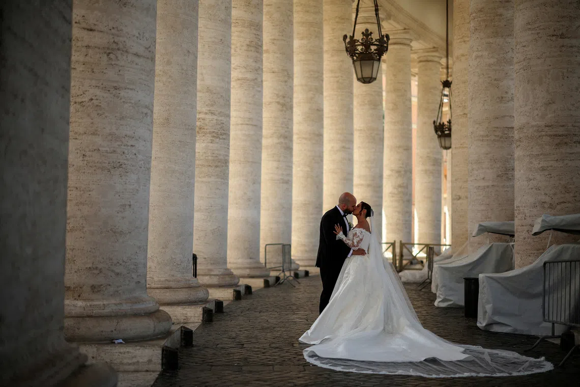 FILE PHOTO: A couple kiss during their wedding photo session under the Vatican colonnade in the Vatican, April 29, 2025. REUTERS/Stoyan Nenov/File Photo