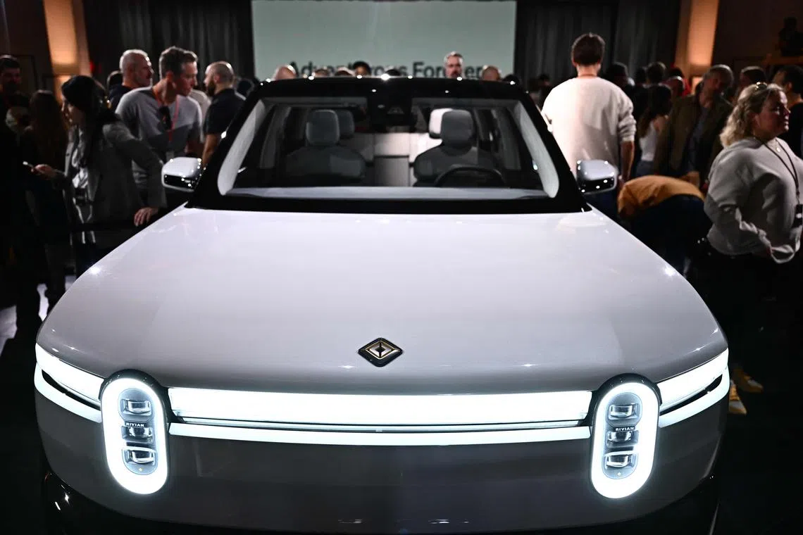 TOPSHOT - Attendees look at the new Rivian R2 electric vehicle at the Rivian South Coast Theater in Laguna Beach, California, on March 7, 2024. (Photo by Patrick T. Fallon / AFP)