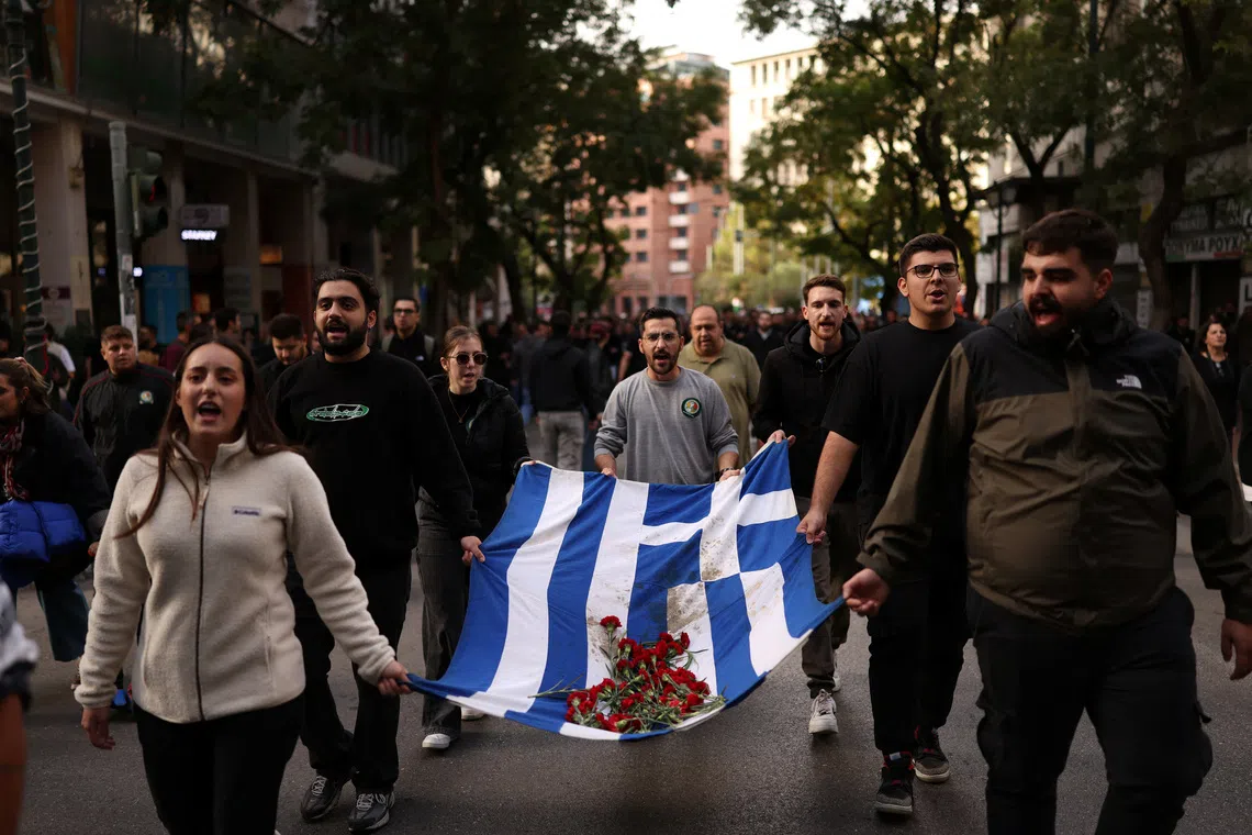 Athens’ Polytechnic students carry a blood-stained Greek flag with red carnations, during a march marking the 52nd anniversary of a 1973 student uprising against the military junta that ruled the country at the time, in Athens, Greece, November 17, 2025. REUTERS/Stelios Misinas