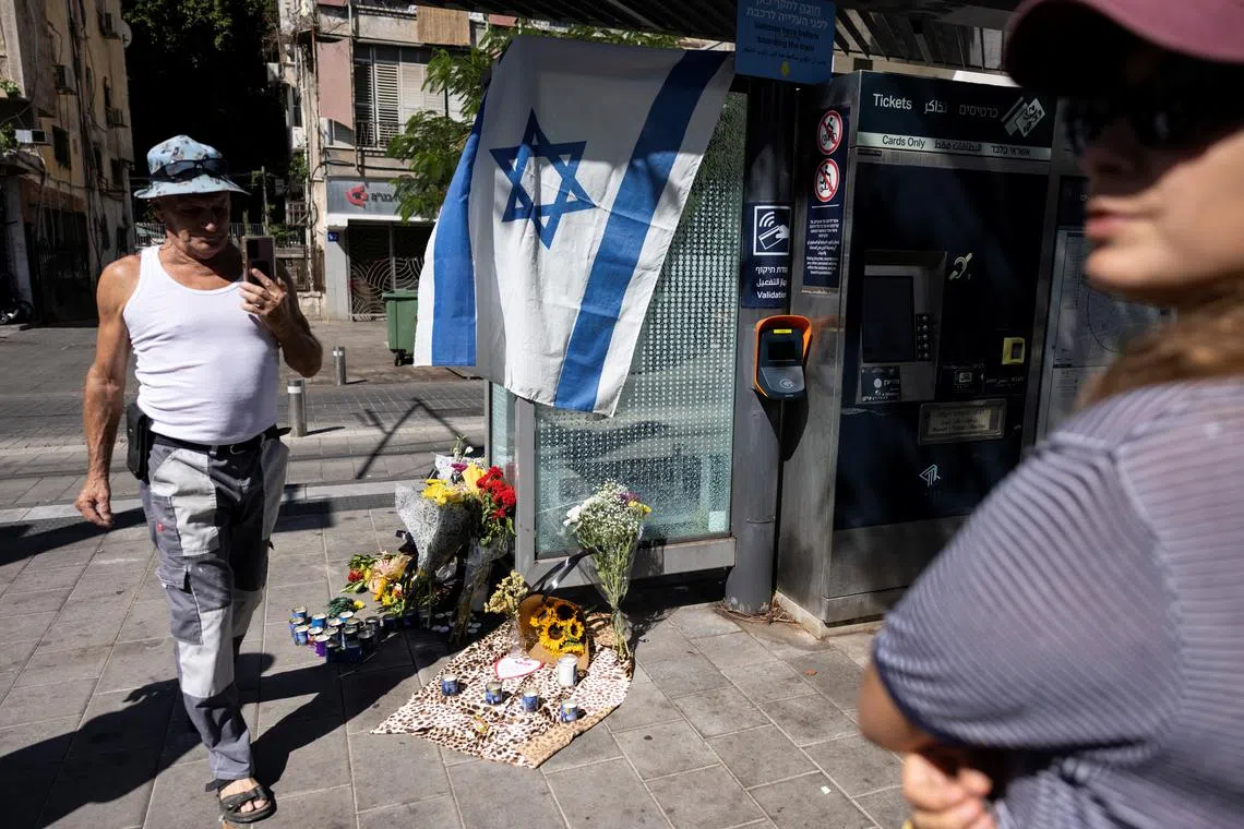 A man walks by flowers laid as a sign of respect for the people killed the evening before in a fatal shooting attack in Jaffa, Israel, October 2, 2024. REUTERS/Nir Elias