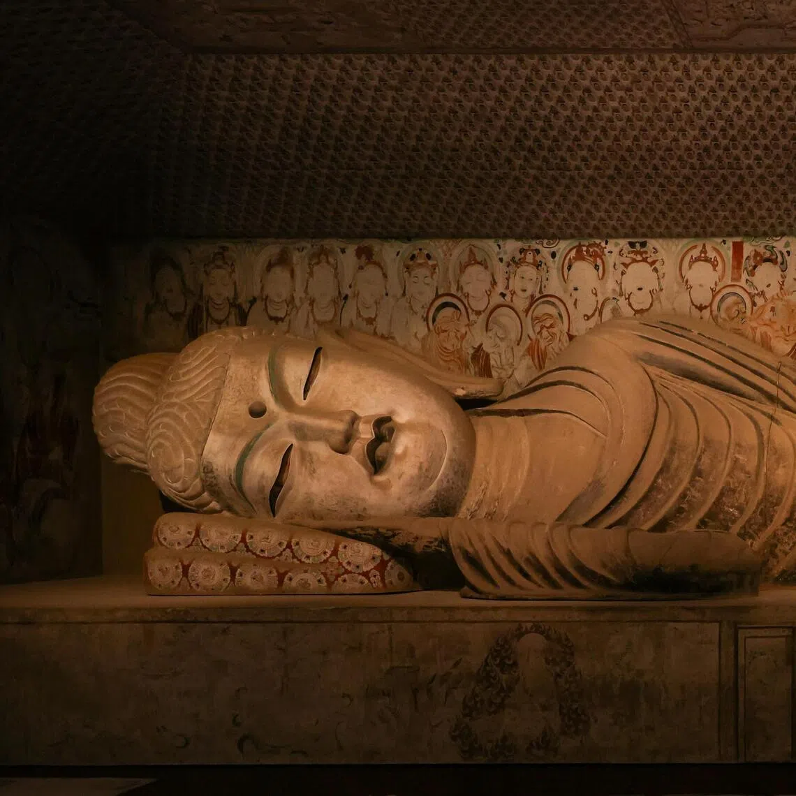 A contractor touching up a 13m-long Buddha sculpture ahead of the Sacred Caves: Dunhuang, Buddhism, And The Silk Road exhibition at the Asian Civilisations Museum.