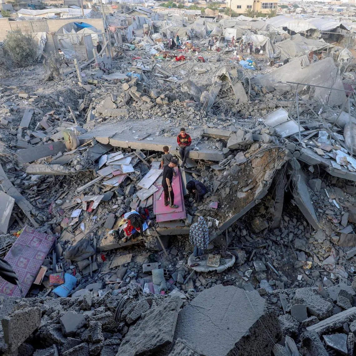 Palestinians inspect the site of an Israeli strike on a house whose residents were warned to evacuate before the attack, near a tent camp sheltering displaced people that was damaged in the strike, in Khan Younis in the southern Gaza Strip June 7, 2026. REUTERS/Ramadan Abed