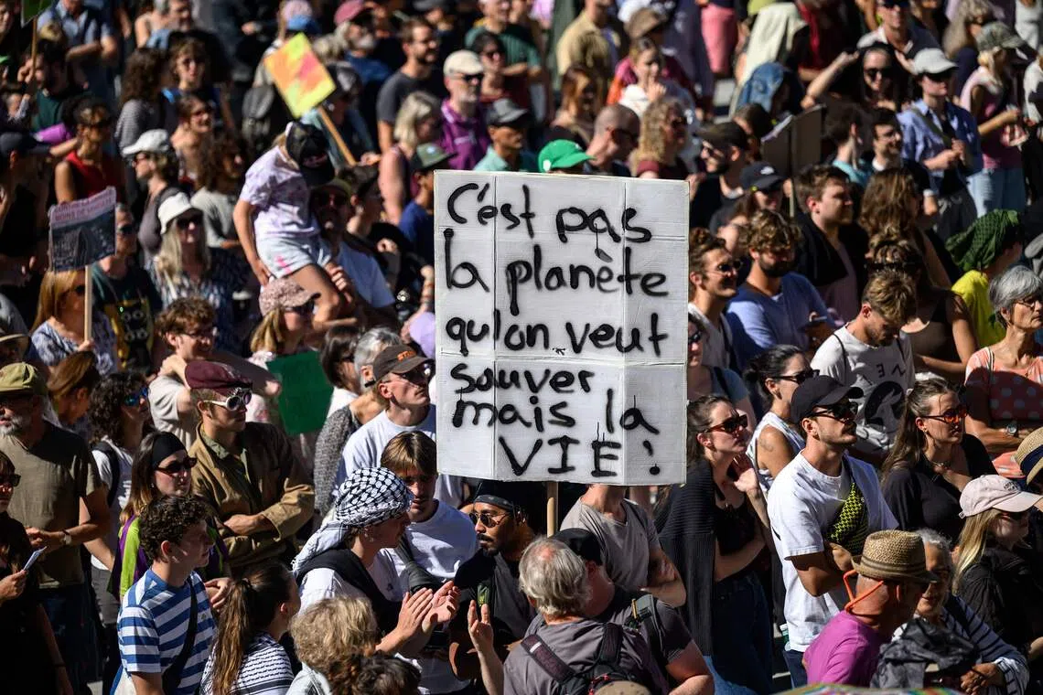 A protester holds a placard reading in French “It’s not the planet we want to save, but life!” during a climate protest under the slogan “No 50°C summers!” in Lausanne on Sept 19.